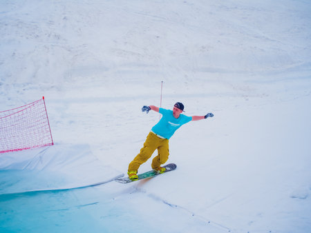 Russia, Sochi 11.05.2019. A snowboarder in a cap backwards and bright clothes flies into the water...