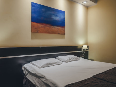 Sochi, Russia - 24 February 2020. Fragment of the room with a blue orange picture hanging over the double bed. Photo using filterのeditorial素材