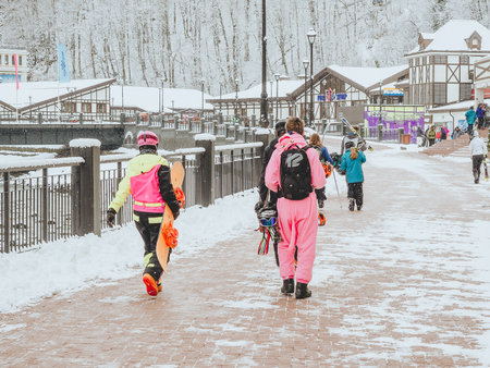 Sochi, Russia - 25 February 2020. People in ski suits with equipment walk along the sidewalk along the river in a ski resortのeditorial素材