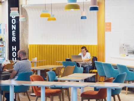 Russia, Sochi 02.11.2021. A woman with a laptop sits at a table in a cafe. Airport cafe visitors waiting for departure. Soft focusのeditorial素材