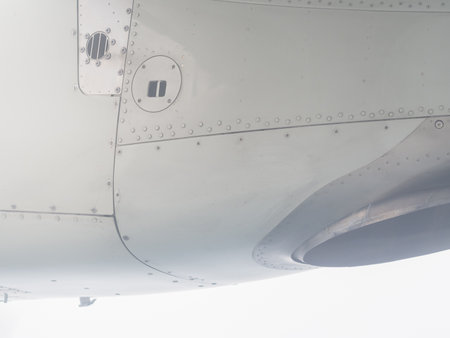 Fragment of an aircraft wing with seams and metal screws. Close-up photo. View from the porthole