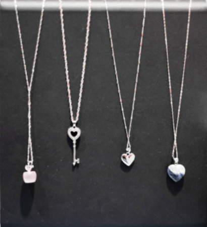 Jewelry pendants on chains hang on a black background. Defocused photo. Precious gift.の写真素材