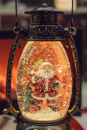Luminous decorative Christmas lantern with santa figurine inside. Elegant festive interior decoration. Closeup photoの写真素材