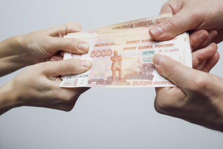 Male and female hands firmly hold a pack of five thousand ruble bills. Soft focus.の写真素材