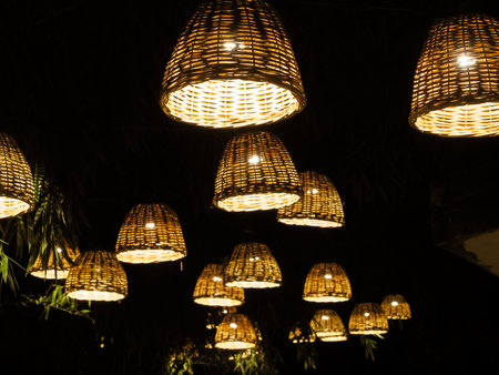 Many lamps with wicker lampshades illuminate the dark bamboo alley in the park.の写真素材