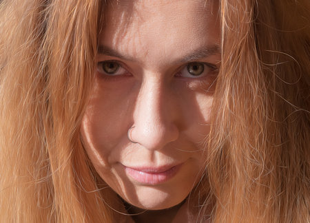 Portrait of a fair-haired woman with serious facial expressions. Closeup photo in full screen