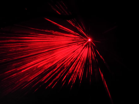 A bright spotlight projects red long beams in a dark space. Laser show. Blurred imageの写真素材