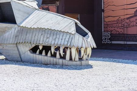 Russia, Sochi 14.05.2022. Giant wooden skull of a toothy dragon on a platform of rubble. Fairy tale character. Folk decor in the amusement parkのeditorial素材