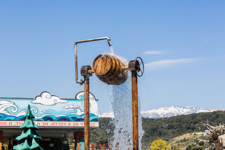 Russia, Sochi 14.05.2022. A stream of water pours out of a wooden barrel in an amusement park...