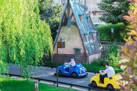 Russia, Sochi 14.05.2022. A father in a childrens yellow car follows his son in a blue car. Entertainment for children and adults. Childrens circuit in the amusement park. Fairytale childrens townのeditorial素材