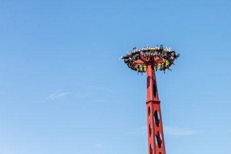 Russia, Sochi 14.05.2022. A giant rotating extreme attraction with people hanging upside down in it against the blue sky. Adrenaline fun at the amusement parkのeditorial素材