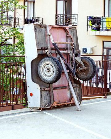 Car trailer. Overturned cart. Overturned wheelbarrow. An overturned car trailer stands at the fence...