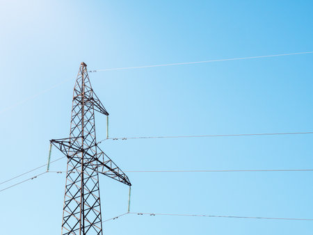 Metal electric pole with wires against the sky. Bottom view