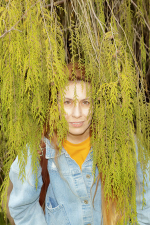 A woman hides in a cypress. Camouflage in the branches of a tree.の写真素材