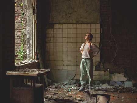Woman inside an ancient ruined building. Old littered broken room. Walk through the old ruins. House destroyed by warの写真素材