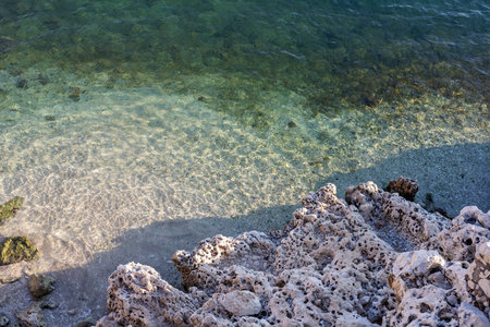 Transparent waters meeting a rocky shore under a clear sky.