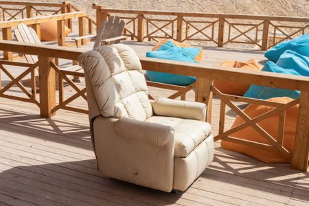 Sunlit scene featuring a cozy recliner and vibrant bean bags on a rustic wooden deck. perfect for relaxation and outdoor gatherings, this inviting setup offers a warm and tranquil atmosphere. suitable for depicting leisure and comfort in summer settings.の写真素材