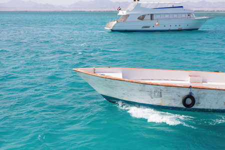This serene image captures two white boats gliding through vibrant turquoise waters against a...