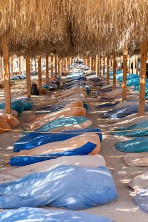 Relax under straw umbrellas on a sandy beach, where colorful towels add vibrancy to the serene coastal setting. the interplay of sunlight and shadows creates a tranquil atmosphere, perfect for a summer escape or leisurely holiday at an exotic seaside location.の写真素材