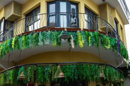 Lush greenery adorning yellow building with curved balcony.の写真素材