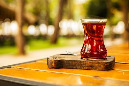 Steaming glass of Turkish tea on wooden table in garden setting.の写真素材