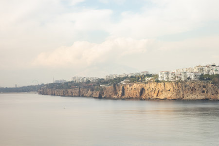 Coastal cliffs and urban skyline against cloudy sky.の写真素材