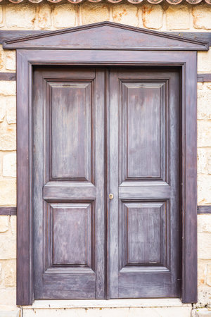 Rustic wooden door with stone wall background in sunlit outdoor setting.の写真素材