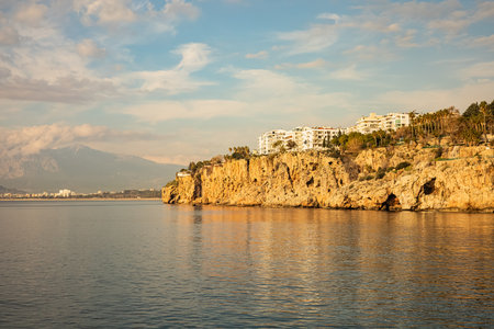 Coastal cliffs with buildings overlooking tranquil sea and mountain view.の写真素材