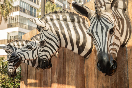 Lifelike zebra heads sculpture on wooden urban fence.の写真素材