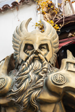 Bronze warrior statue with helmet and beard in outdoor setting.の写真素材