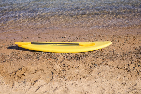 Yellow surfboard with paddle on sandy beach by the sea. Summer.の写真素材