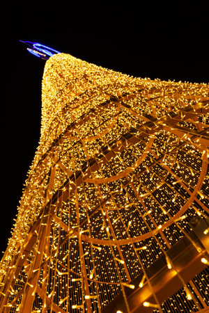 A Christmas tree frame made of golden lights from garlands against the night sky.の写真素材