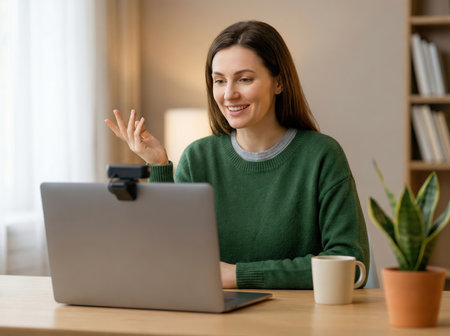 Happy woman talking during a video call from home office.の素材