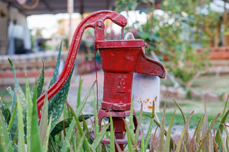 Weathered red water pump in outdoor garden.