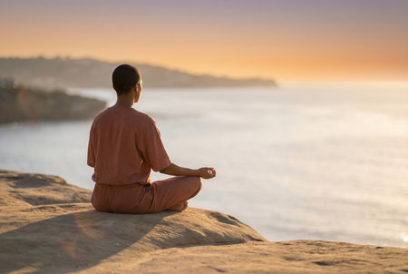 Meditating person by ocean at sunset.の素材