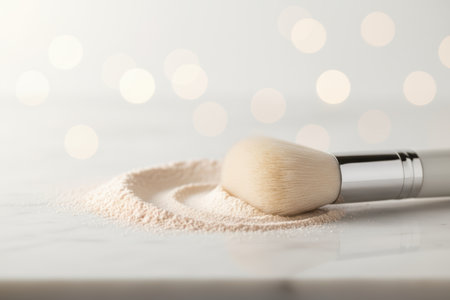 Makeup brush and powder on light surface with bokeh background.の素材
