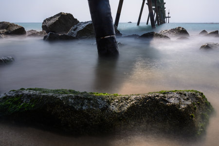 Half shining rock & sea vs the shadows projected by a bridge at the rocky coast of Badalona, Spainの写真素材