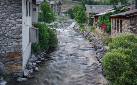 Long exposure caption of a river passing between homes, various trees & foliage at Isil, Spainのeditorial素材