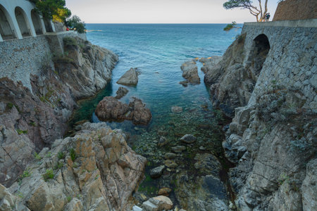 A little rocky bay between two constructions with arches & the deep blue mediterranean sea & the...