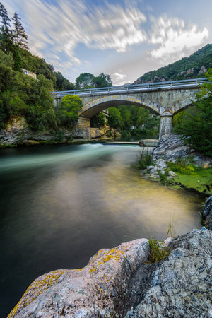 A colorful scene, a stone bridge over a silky river after a rockの写真素材