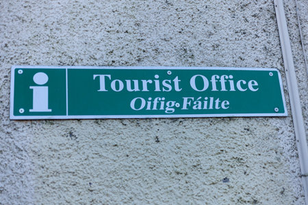 Green tourist office sign on a white wallの写真素材