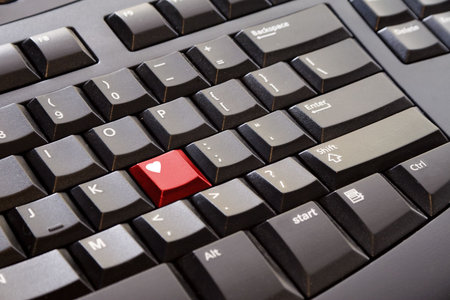 A red heart key on a black computer keyboard