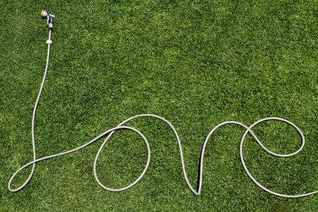 Word love written in a garden hose on a lush lawnの写真素材