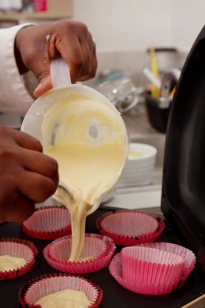 Pasty chef pouring cupcake batter into patties