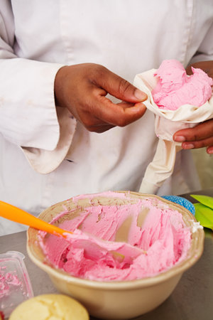 Pastry chef filling a piping bag of pink icing frostingの写真素材