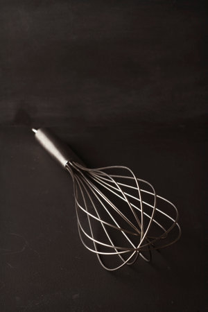 Creative still life of a single whish kitchen utensil on blackboard backgroundの写真素材