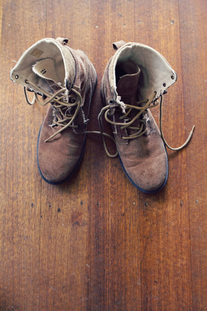 Overhead of worn old walking or work boots on rustic wooden floorの写真素材