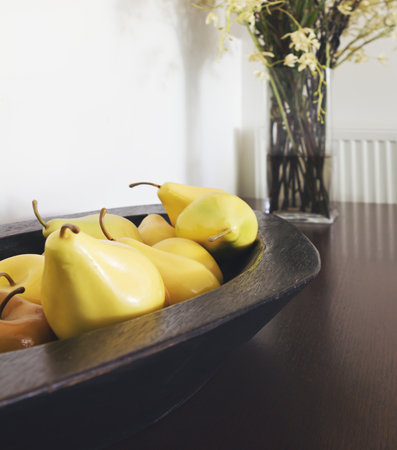 Close up of yellow pear decorations in a rustic wooden bowl interior designed homeの写真素材