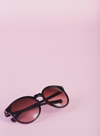 Pair of women's sunglasses on sparse pastel pink backgroundの写真素材