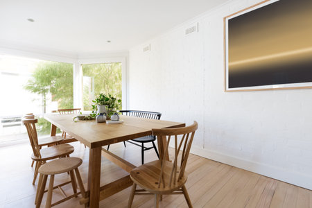 Scandinavian styled white dining room interior with contemporary artwork and pot plant